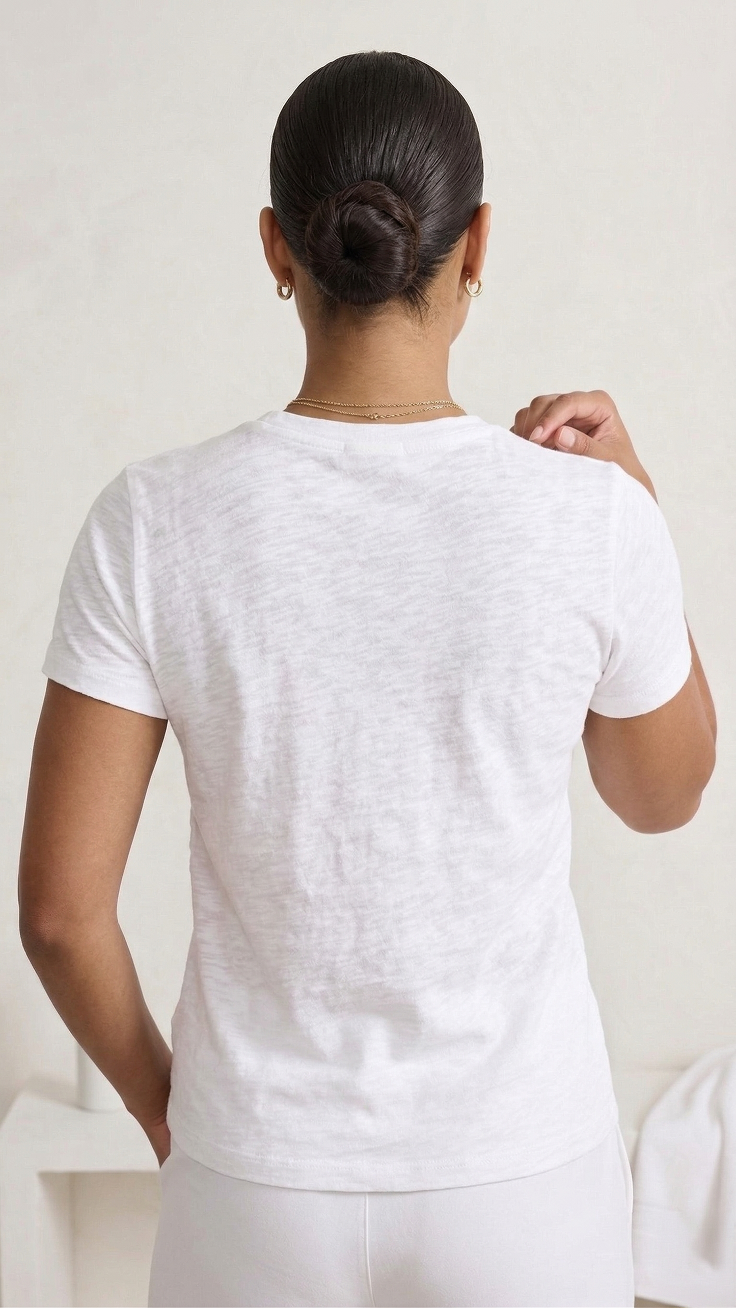 Person wearing a plain white t-shirt against a light background