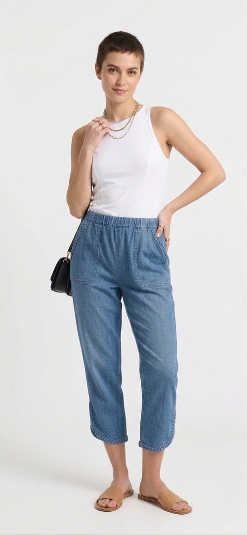 Woman wearing a white sleeveless top and blue pants on a white background