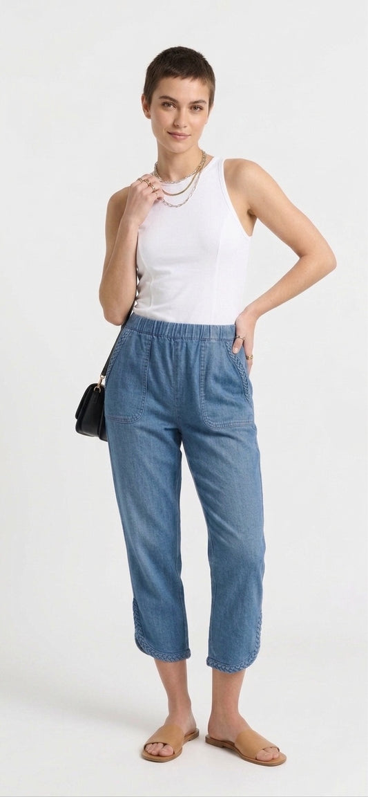 Woman wearing a white sleeveless top and blue pants on a white background